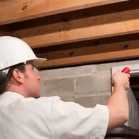 Termite inspection technician checking a basement wall and framing for termite activity in San Francisco, CA